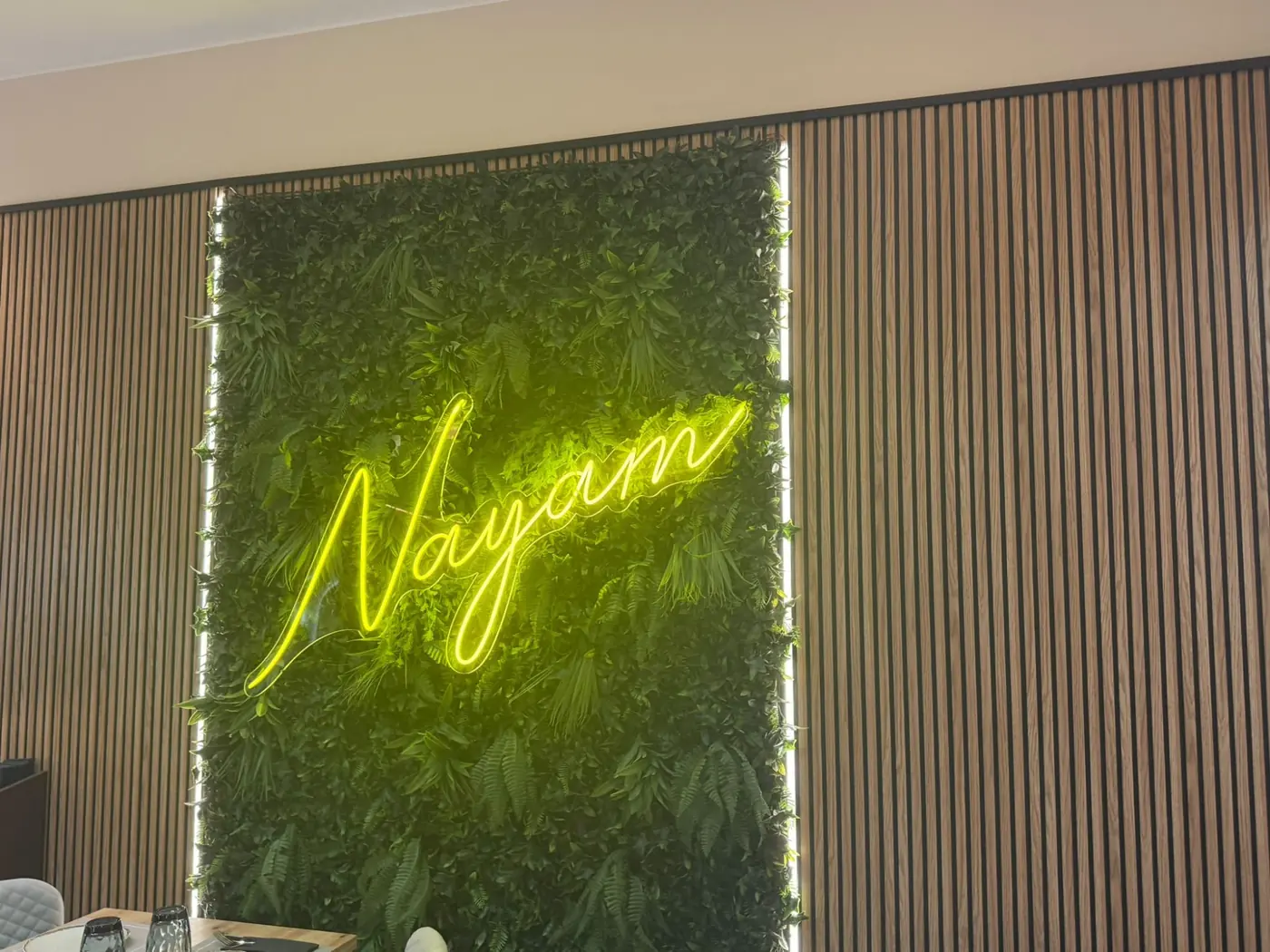 Neón de Nayam sobre muro vegetal